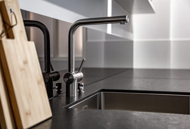 New modern steel faucet and kitchen room sink close up. Modern designer chrome water tap over stainless steel kitchen sink close up.